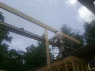 Carpenter setting a ridge beam over a new addition frame — Ice Dam Removal by Roofing Brothers in Roberts
