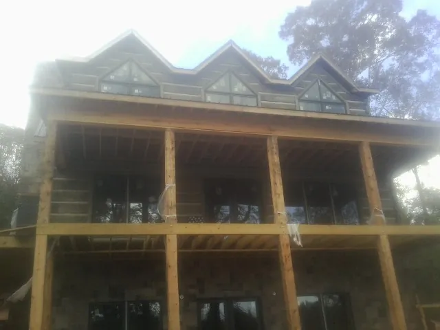 Dormers and porch framing on a large log home under construction — Roof Coating work by our crew in Roberts