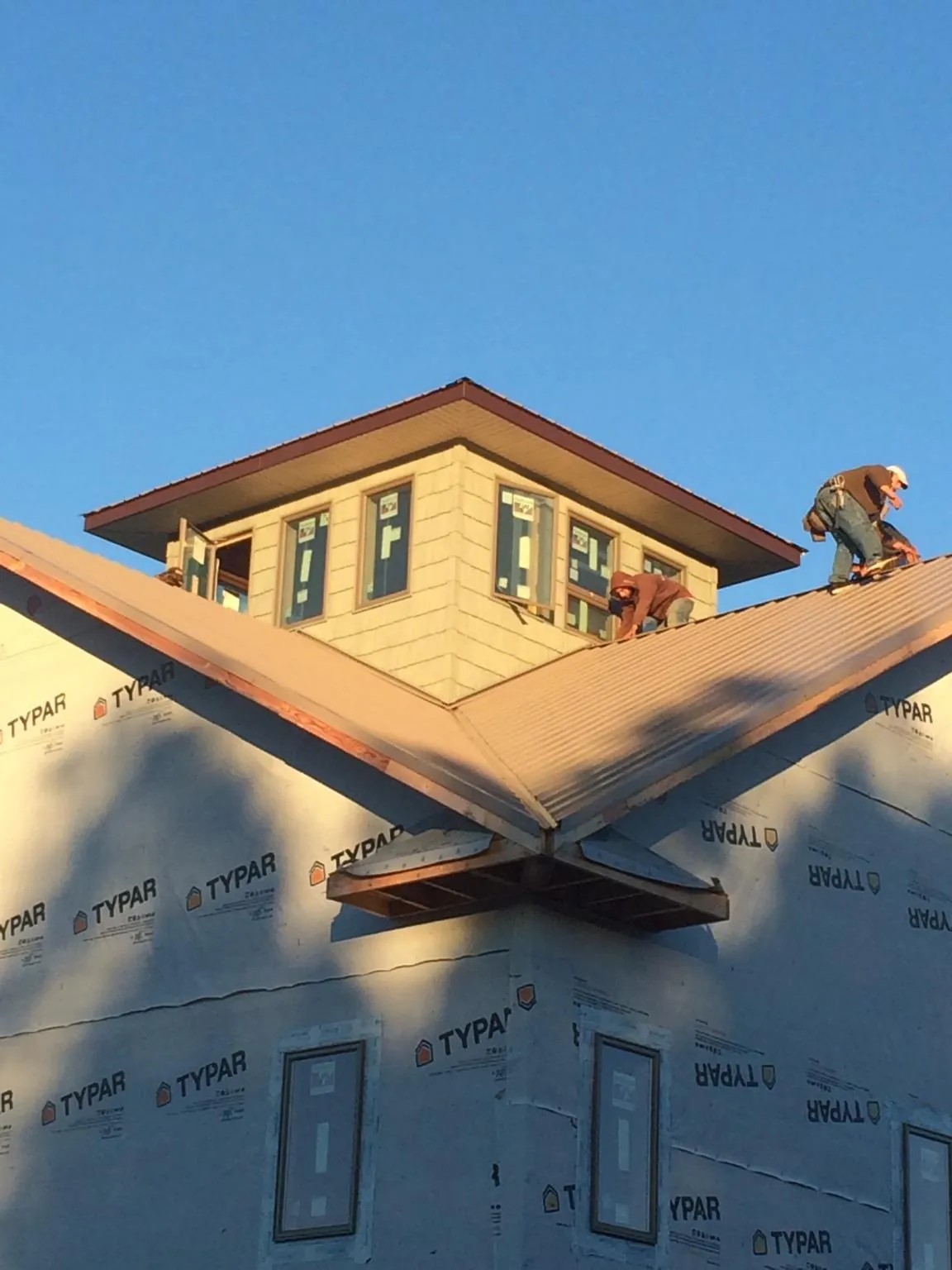 Roofers working around a rooftop cupola on a new metal roof at sunset — Roof Waterproofing in Roberts by Roofing Brothers